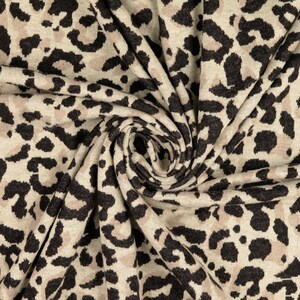 Könnte beinhalten: Nahaufnahme eines beige-braunen Stoffes mit Leopardenmuster. Der Stoff ist weich und texturiert, und der Druck ist dezent und elegant.