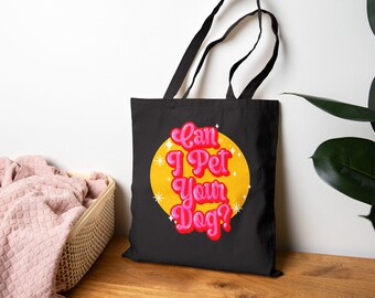 May include: Black tote bag with the text "Can I Pet Your Dog?" in pink and red lettering, set against a yellow circle with star accents. The bag has black handles and is likely made of canvas or a similar material.