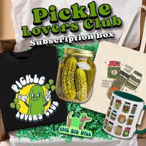 May include: A subscription box for pickle lovers, featuring a black t-shirt with a pickle graphic, a tote bag, a mug, a jar of pickles, and a sticker. The box is filled with green paper and the text "Pickle Lovers Club Subscription Box".
