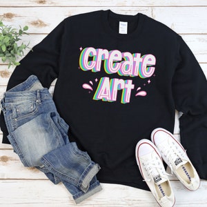 May include: Black sweatshirt with the text "create art" in rainbow colors. The text is in a retro, 3D style.