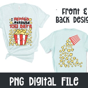 A light blue t-shirt with a front and back design. The front design features a cartoon popcorn bucket with a smiling face and the text "I popped through 100 days". The back design features a cartoon popcorn bucket spilling popcorn.