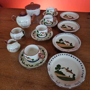 Op de afbeelding: Een crèmekleurige vintage theeset met een theepot, suikerpot, melkkan, kopjes, schotels en borden. De set heeft bruine accenten en een huisontwerp. Sommige stukken zijn voorzien van de tekst "Take a Cup of Tea" en "Say little but think much."