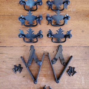 Può includere: Sei tiretti per cassetti in metallo nero con disegni decorativi e due cerniere per armadi in metallo nero con viti.