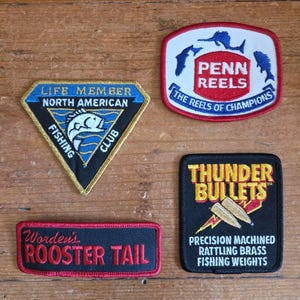 Set van 4 vintage vispatches van Penn Reels, Rooster Tail en Thunder Bullets, nieuw in doos (NOS), strijkpatches voor kunstaas en kleding. Retro vispatchcollectie.