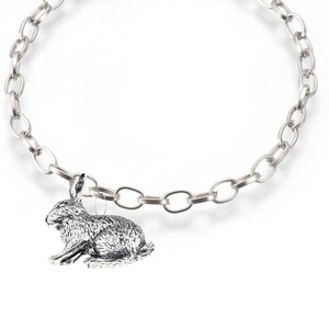 May include: A silver chain bracelet with a silver rabbit charm. The rabbit is sitting on its hind legs with its ears up.