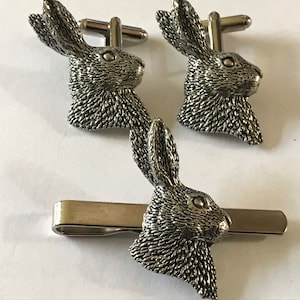 May include: A set of silver-toned cufflinks and a tie bar featuring a detailed rabbit head design.
