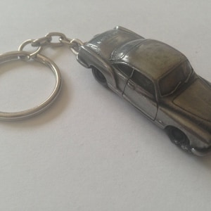 Könnte beinhalten: Ein silberner Schlüsselanhänger mit einem detaillierten Modell eines klassischen Volkswagen Käfers.