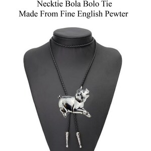 Pode incluir: Um laço bolo preto com um pingente de porco prateado. O laço está em um busto de manequim preto. "Check out my range of Necklace Necktie Bola Bolo Tie Made From Fine English Pewter" está escrito acima do busto.