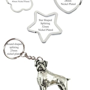Può includere: Un portachiavi a forma di boxer color argento con un anello diviso. Il portachiavi è attaccato a una catena argentata. L'anello diviso è disponibile in quattro forme: fiore, cuore, stella e rotondo. Il testo sull'immagine recita: "Flower Shaped Splitring 40mm Nickel Plated", "Heart Shaped Splitring 28mm Nickel Plated", "Star Shaped Splitring 32mm Nickel Plated" e "Round shaped splitring 25mm nickel plated".