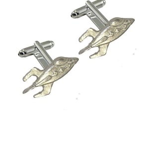 May include: A pair of silver cufflinks featuring a stylized spaceship design. The cufflinks have a polished silver finish and a classic design.