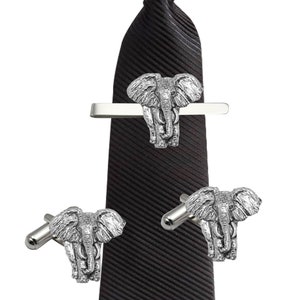 May include: A black tie with a silver elephant tie clip and a pair of silver elephant cufflinks.