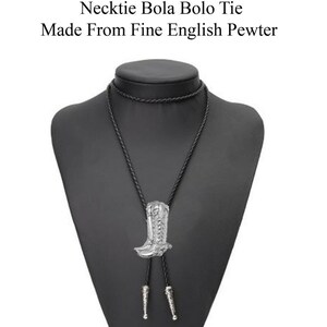 May include: Black bolo tie with a silver boot pendant. The pendant is detailed with a boot design. "Necktie Bola Bolo Tie Made From Fine English Pewter" is written in white text on a white background.
