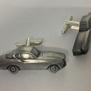 Op de afbeelding: Een paar zilveren manchetknopen met een vintage auto-ontwerp. De manchetknopen zijn gemaakt van tin en hebben een gedetailleerd ontwerp van een klassieke auto.