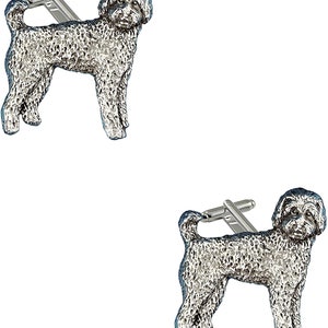 Puede incluir: Un par de gemelos de plata con una escultura en miniatura detallada de un perro doodle.