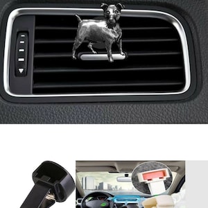 Op de afbeelding: Auto ventilatieclip kit met een zilveren hondenbeeldje. De afbeelding toont een zwart autoventilatie met een decoratieve hondenclip en twee extra clips. De tekst "Car Vent Clips Air Freshener Clip Kit" staat bovenaan.