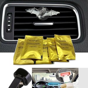 May include: A set of car air freshener clips with a bat design. The clips are black and come with five small, gold foil packets of air freshener. The packets have Chinese text and English text that says "Peach Flavor", "Lemon", "Lavender", and "Floral Fine".