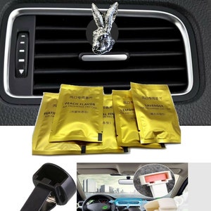 Puede incluir: Un conjunto de ambientadores para coche en bolsas de papel de aluminio dorado con diferentes aromas, incluyendo melocotón, lavanda y limón. Las bolsas están etiquetadas en chino e inglés. El conjunto también incluye dos clips de ventilación de coche de plástico negro.