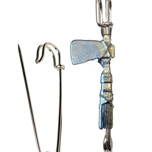 May include: A silver-toned tomahawk and peace pipe pin with a safety pin fastening.