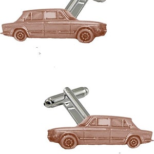 May include: A pair of silver cufflinks with a brown car design. The car is a classic sedan with a rounded body style.