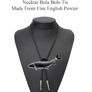 May include: A black bolo tie with a silver fish pendant. The tie is displayed on a black mannequin. The text "Check out my range of Necklace Necktie Bola Bolo Tie Made From Fine English Pewter" is displayed above the mannequin.
