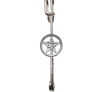 May include: Silver-toned pentagram brooch with a circular design. The brooch has a safety pin closure.