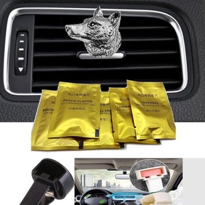 May include: A set of car vent clips featuring a silver wolf head design. The clips are used to hold air fresheners in the car's air vents. The air fresheners are in small gold foil packets with Chinese text and English text that says "Peach Flavor", "Lemon", and "Lavender".