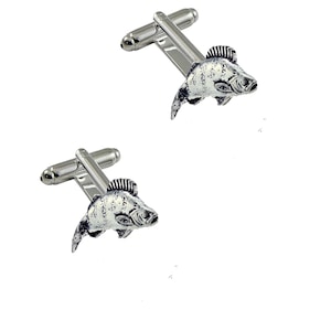 Könnte beinhalten: Ein Paar silberne Manschettenknöpfe mit einem detaillierten Fischdesign. Die Fische sind nach rechts gerichtet und haben eine strukturierte Oberfläche.