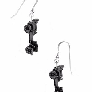 Op de afbeelding: Een paar zilveren oorbellen met een miniatuur jeep-bedel. De jeep is zilver en heeft zwarte banden.