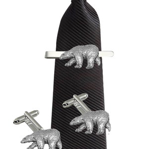 Op de afbeelding: Een zwarte stropdas met een zilveren stropdasclip in de vorm van een ijsbeer en bijpassende manchetknopen. De ijsbeer is een gedetailleerd en realistisch ontwerp.