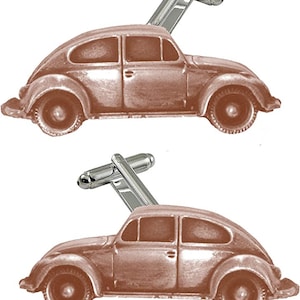 May include: A pair of cufflinks featuring a vintage car design. The cufflinks are a bronze color with silver-colored posts. The car has detailed features, including windows, wheels, and a classic shape. These accessories are suitable for formal wear.