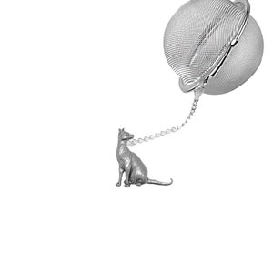 May include: A silver tea infuser, featuring a mesh ball and a chain leading to a seated cat figurine. This infuser is designed for loose leaf tea. The cat figurine provides a decorative element.