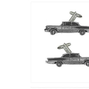 May include: A pair of cufflinks featuring a vintage car design. The cufflinks are made of pewter and have a silver finish. The cars are black with a white stripe and have a chrome bumper.
