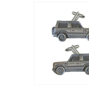 Könnte beinhalten: Ein Paar silberne Manschettenknöpfe mit einer detaillierten Miniatur eines grauen SUV. Die Manschettenknöpfe sind zum Tragen an einem Hemdmanschetten gedacht.