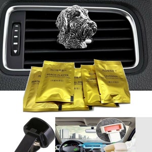 Puede incluir: Un conjunto de clips para ambientadores de coche con una figurita de perro plateada. Los clips son negros y vienen con una variedad de aromas, incluyendo melocotón, limón y lavanda. El embalaje es dorado y presenta caracteres chinos.