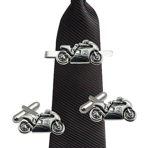 Könnte beinhalten: Eine schwarze Krawatte mit einem silbernen Motorrad-Krawattenclip und passenden Manschettenknöpfen. Das Motorrad hat die Nummer "12" an der Seite.