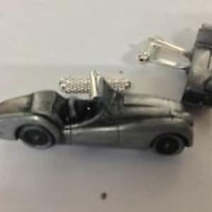 May include: A pair of silver cufflinks featuring a detailed miniature model of a classic sports car.