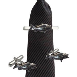 May include: A black striped tie with a silver tie clip featuring a bass fish. The image also shows a pair of cufflinks with bass fish designs.