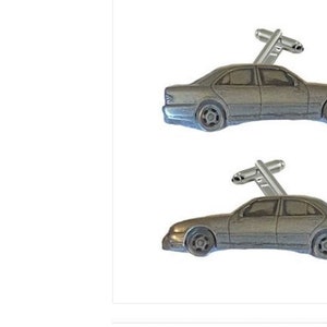 Könnte beinhalten: Ein Paar silberne Manschettenknöpfe mit einem detaillierten Miniatur-Autodesign. Jeder Manschettenknopf hat einen silbernen Schlüssel auf dem Auto.