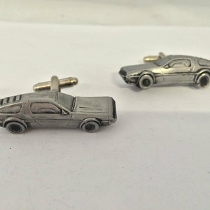 Könnte beinhalten: Ein Paar silberne Manschettenknöpfe in Form eines DeLorean-Zeitmaschinenautos.