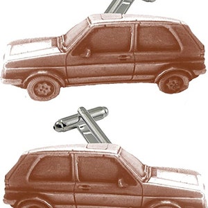 May include: A pair of silver cufflinks featuring a brown car design. The car is a classic hatchback model with a silver roof.
