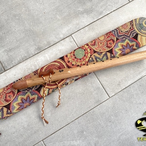 Peut inclure: Une flûte amérindienne en bois avec un étui de transport à motifs brun et noir. L'étui est doté d'une fermeture à cordon et d'un pompon décoratif. La flûte est en bois naturel et a un design simple.