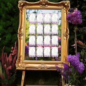 May include: A gold-framed mirror with a seating chart displayed on individual cards. The cards are decorated with floral designs and purple accents. The mirror is propped up on a wooden easel, surrounded by greenery and purple flowers.