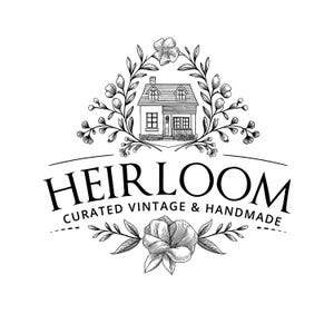 May include: Black and white illustration of a house with a flower wreath above it. The text "HEIRLOOM CURATED VINTAGE & HANDMADE" is below the house.
