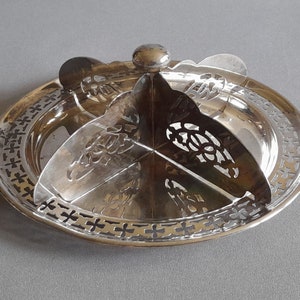 May include: Silver plated serving dish with a decorative, openwork design. The dish has a central, rotating section with four compartments.