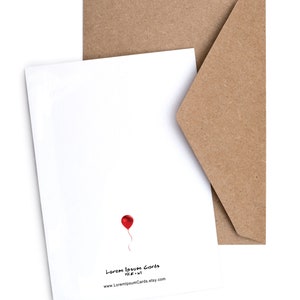 May include: A blank white card with a red balloon and the text "Lorem Ipsum Cards" and "www.LoremIpsumCards.etsy.com". The card is sitting on a brown envelope.