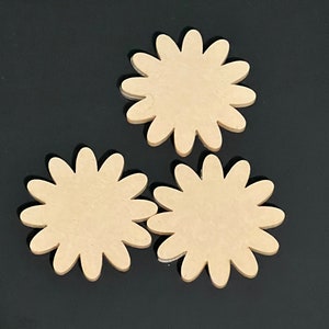 May include: Three unfinished wooden flower-shaped cutouts. The cutouts are beige and have a smooth surface.