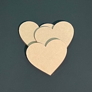 May include: Three unfinished wooden heart shapes stacked on top of each other. The hearts are light brown and have a smooth surface.