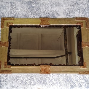 May include: A rectangular mirror with a gold frame and copper accents. The frame has a distressed look and is decorated with rivets.