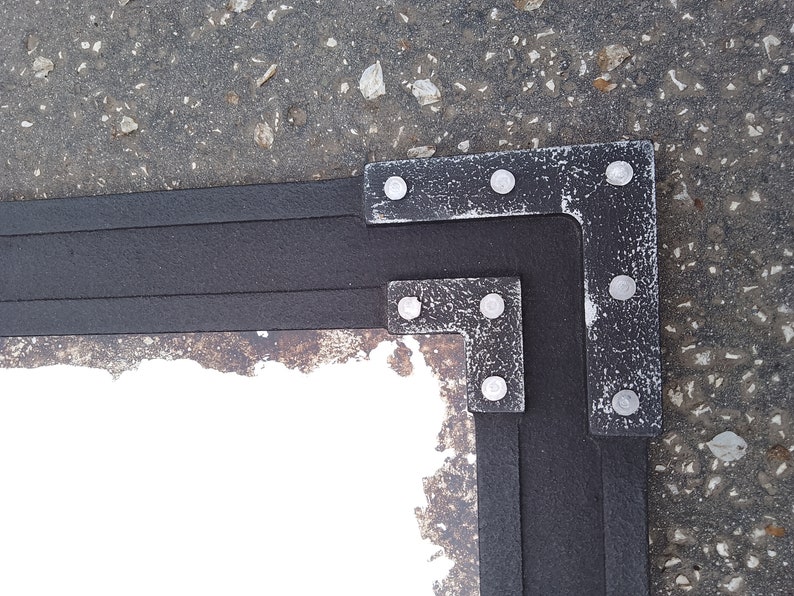 May include: A corner of a black frame with a distressed silver finish. The frame has a white background and is made of wood. The frame is decorated with silver metal corner pieces.