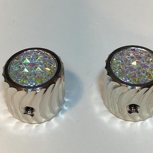 May include: Two silver guitar knobs with a swirl design and iridescent crystal tops.